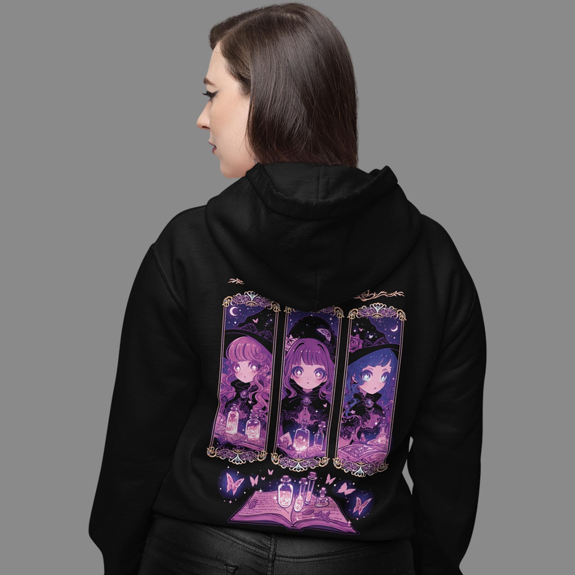 Three-quarter back view of a woman wearing the Coven Sisters Kawaii Witch Hoodie on a grey background, highlighting the detailed purple witch triptych artwork.