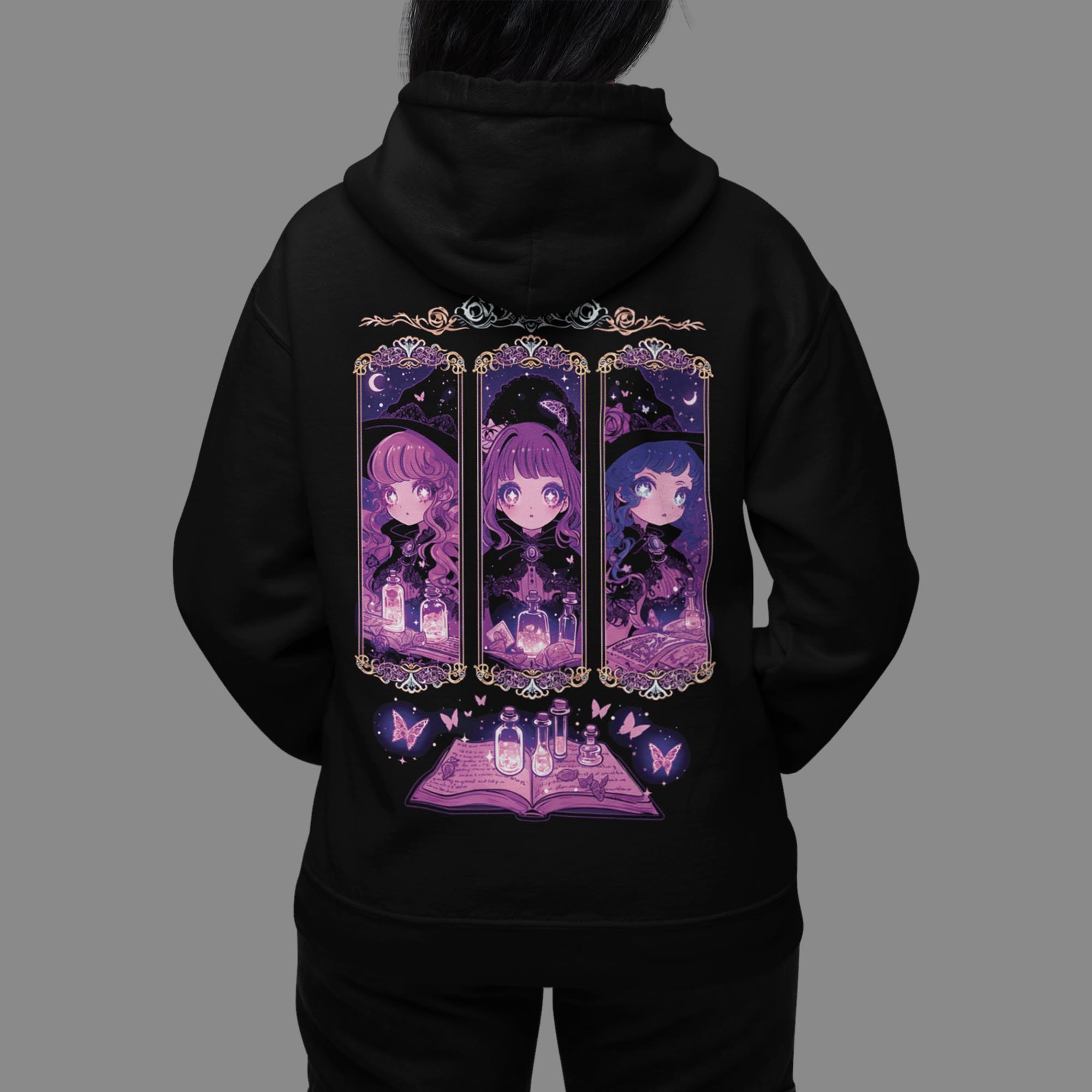 Studio shot of a woman facing away in a black Coven Sisters Kawaii Witch Hoodie, clearly showing the full witch sisters and spellbook back graphic.